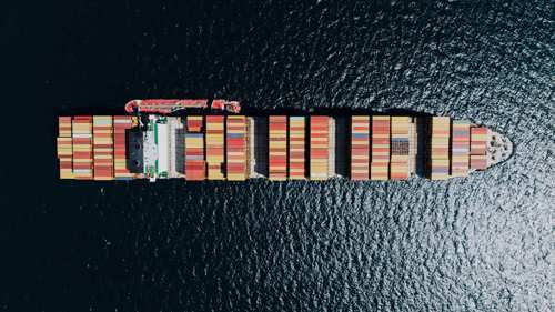 directly above a fully loaded cargo ship on a sea